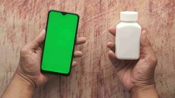 mão aguarde uma inteligente telefone com verde tela e médico comprimido recipiente video