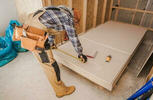 General Construction Worker in His 40s Measuring Drywall Boards photo