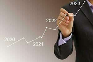 Man's hand pointing graph of success in 2022 year. Growing business concept photo