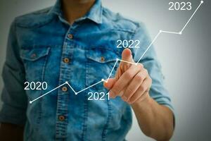 Man's hand pointing graph of success in 2022 year. Growing business concept photo