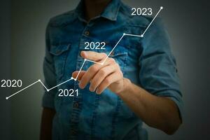 Man's hand pointing graph of success in 2022 year. Growing business concept photo