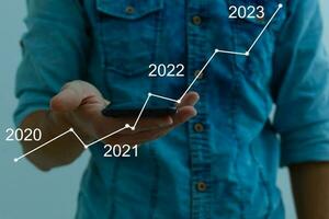 Man's hand pointing graph of success in 2022 year. Growing business concept photo