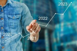 Man's hand pointing graph of success in 2022 year. Growing business concept photo