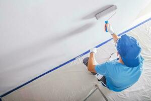 Male Construction Worker Painting Walls White photo
