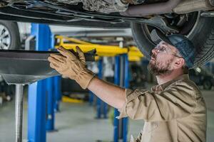 Car Mechanic Changing Vehicle Engine Oil photo