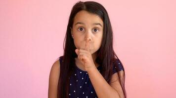 Portrait of an emotional 8-year-old girltaped her mouth. pink background photo