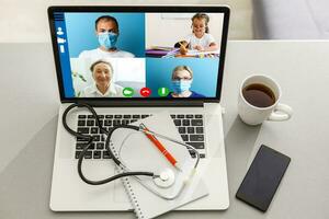 Close-up Of Doctor Having Video Conference On Laptop At Wooden Desk photo