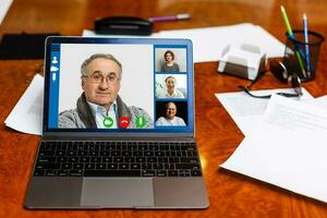 Close-up Of Businessman Video Conferencing On Laptop At Desk In Office photo