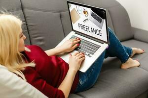 Elegant young female business woman using a laptop sitting on a sofa at home photo