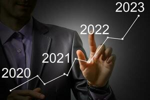 Man's hand pointing graph of success in 2022 year. Growing business concept photo