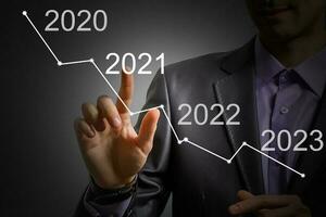 Man's hand pointing graph of success in 2021 year. Growing business concept photo