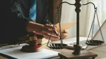 Business and lawyers discussing contract papers with brass scale on desk in office. Law, legal services, advice, justice and law concept picture with film grain effect video