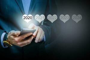 Man holding smartphone in hand display luminous 2020 number calendar year, connecting line virtual holographic glowing in background. global technology concept. photo