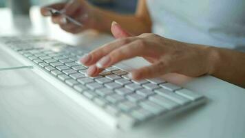 hembra manos mecanografía crédito tarjeta número en computadora teclado. mujer haciendo en línea compra. en línea pago servicio. cerca arriba de mujer manos sostener crédito tarjeta y utilizando computadora para en línea compras video