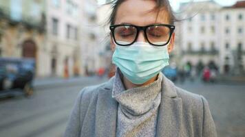pandemia proteção do a covid-19 coronavírus. retrato do uma mulher dentro uma casaco, óculos e uma protetora médico mascarar. óculos névoa acima a partir de respiração video