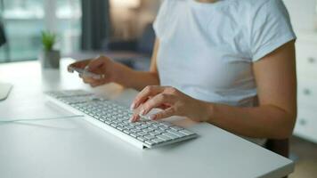 hembra manos mecanografía crédito tarjeta número en computadora teclado. mujer haciendo en línea compra. en línea pago servicio. cerca arriba de mujer manos sostener crédito tarjeta y utilizando computadora para en línea compras video