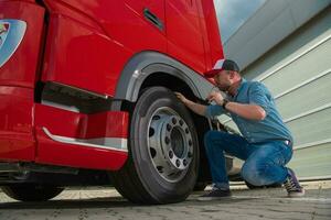 Responsible Truck Driver Checking Wheel Before Starting Route photo