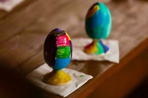 Pascua, familia, vacaciones y concepto de niño - cerca de la niña y la madre coloreando huevos para Pascua foto