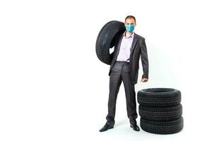 man in protective mask. Sale of cars in the showroom, closeup of the car wheel photo