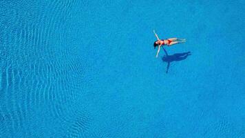 aéreo ver de hombre inmersiones dentro el el piscina mientras niña es acostado en un rosquilla piscina flotador video