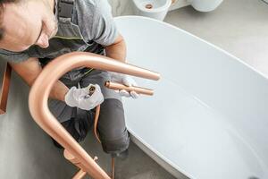 Handyman Attaches Faucet Kit To Complete Tub Installation. photo