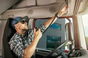 Caucasian Semi Truck Driver Talking by CB Radio photo