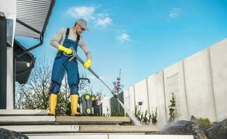 hombres Lavado su patio interior jardín hormigón camino y escalera utilizando presión lavadora foto