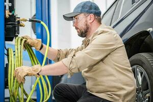 Car Mechanic Preparing to Inflate Vehicle Tires with Compressor photo