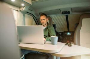 Men Working Straight From His Camper Van While on a Road Trip photo