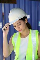 South East Asian beautiful young Malay Chinese woman wearing white yellow safety helmet vest sting on forklift read study look photo