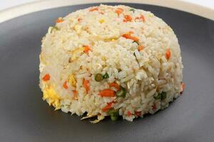 Chinese style egg fried rice with carrot green spring onion on black plate off white rim over white background photo