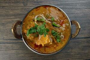 Haleem stew wheat barley lentils mutton goat chicken beef meat bone spice served in a copper brass pot over rustic wood background photo