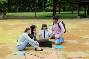 joven asiático malayo chino hombre mujer al aire libre parque libro archivo carpeta ordenador portátil computadora teléfono sentar estar estudiar mezclarse foto