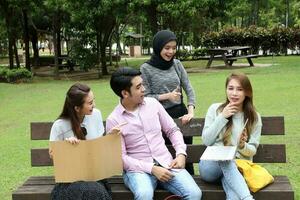 joven asiático malayo chino hombre mujer al aire libre parque libro archivo carpeta ordenador portátil computadora teléfono sentar estar estudiar mezclarse foto