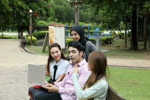 joven asiático malayo chino hombre mujer al aire libre parque libro archivo carpeta ordenador portátil computadora teléfono sentar estar estudiar mezclarse foto