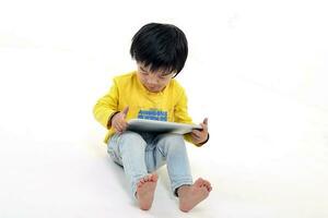 South East Asian young boy child playing tablet tab computer pc on white background photo