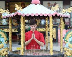 Young south east asian Chinese man woman traditional costume Chinese new year greeting outdoors at temple photo