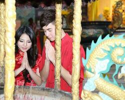 Young south east asian Chinese man woman traditional costume Chinese new year greeting outdoors at temple photo