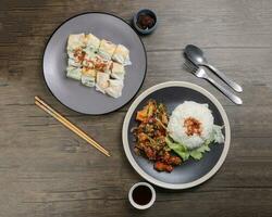 Chinese style Kung Pao Gong Bao Kung Po stair fried chicken and rice noodle roll cheung fun stuffed shrimp chicken vegetable on dark plate sauce fork spoon chopsticks on rustic dark wood table photo