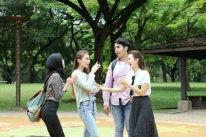 joven asiático malayo chino hombre mujer al aire libre parque libro archivo carpeta ordenador portátil computadora teléfono sentar estar estudiar mezclarse foto