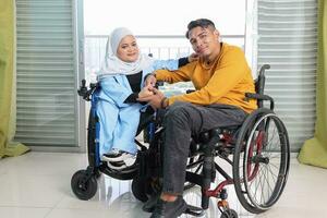 Portrait of young man woman south east Asian malay sitting on wheelchair against window light. Paralyzed waist down. photo