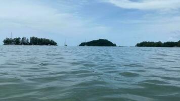 daylight wind small wave on ocean sea water near the beach at straits of Melaka small islands and boats floating photo