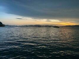 sunset wind small wave on ocean sea water near the beach at straits of Melaka small islands and boats floating photo