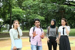 joven asiático malayo chino hombre mujer al aire libre parque caminar estar estudiar hablar discutir punto ordenador portátil archivo libro mochila foto