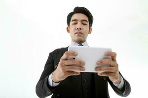 Southeast Asian young office business man wearing suit holding reading using tablet tab on white studio background photo