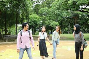 joven asiático malayo chino hombre mujer al aire libre parque libro archivo carpeta ordenador portátil computadora teléfono sentar estar estudiar mezclarse foto