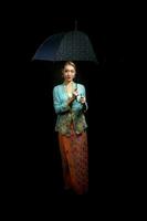 Asian woman in tractional kebaya carrying umbrella on black background photo