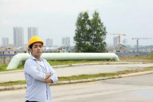 Asian man malay worker engineer management hard hat safety helmet at construction site stand cross arm confident photo