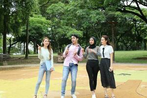 joven asiático malayo chino hombre mujer al aire libre parque libro archivo carpeta ordenador portátil computadora teléfono sentar estar estudiar mezclarse foto