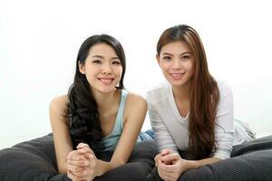 Two Beautiful young south east Asian Chinese relax pillow cushion look at camera on white photo